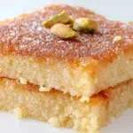 Basbousa semolina cake topped with almonds and soaked in sweet syrup on a serving plate