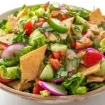 Fattoush salad with fresh vegetables, crispy pita chips, herbs, and tangy dressing served in a bowl
