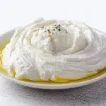 labneh recipe creamy middle eastern strained yogurt dip on wide plate with olive oil pooled in center za'atar pomegranate seeds and warm pita bread