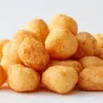 Crunchy chin chin snack pieces piled in a bowl with a golden crispy texture and light sugar coating.