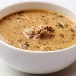 Beniseed soup served in a bowl, made with ground sesame seeds, tender meat, and a rich savory broth.