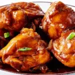 Chicken adobo simmered in a rich savory sauce with garlic, soy sauce, and tender chicken pieces.