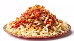 Egyptian koshari served in a bowl with rice, lentils, pasta, crispy onions, and a flavorful tomato sauce.
