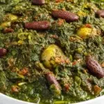 Ghormeh Sabzi herb stew simmered with fresh herbs, tender beef, kidney beans, and dried limes in a rich broth.