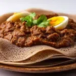 Injera served with Doro Wat, featuring soft Ethiopian flatbread and spicy chicken stew with boiled eggs.
