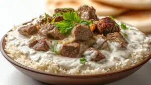 Jordanian mansaf served with tender lamb, aromatic rice, and creamy yogurt sauce, garnished with nuts and fresh herbs.