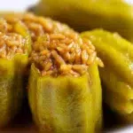 Kousa Mahshi made with tender zucchini stuffed with seasoned rice and meat, simmered in a rich tomato broth.