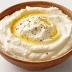 Creamy Lebanese garlic sauce served in a bowl, garnished with a drizzle of olive oil and fresh garlic.