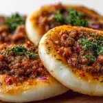 Mini lahmacun bites topped with seasoned minced meat, herbs, and spices, baked until golden and crispy.