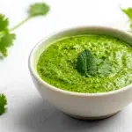 Pudina chutney served in a bowl, made with fresh mint leaves, herbs, and spices for a vibrant green color.