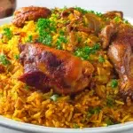 Saudi Kabsa served with fragrant spiced rice, tender chicken, toasted nuts, and raisins on a large serving platter.