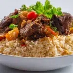 Senegalese Thiebou Yapp served with tender lamb, seasoned rice, and vegetables on a traditional platter.