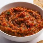 Traditional zaalouk made with roasted eggplant, tomatoes, garlic, and spices, garnished with fresh herbs and olive oil.