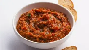 Traditional zaalouk made with roasted eggplant, tomatoes, garlic, and spices, garnished with fresh herbs and olive oil.