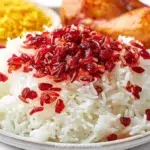 Zereshk Polo barberry rice served with fluffy saffron rice, vibrant barberries, and garnished with pistachios and almonds.