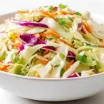 Asian cabbage salad with shredded cabbage, carrots, green onions, and sesame dressing topped with crunchy almonds and sesame seeds