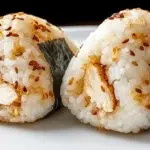 Chicken onigiri made with seasoned rice shaped into triangles and filled with savory chicken, wrapped in roasted seaweed.