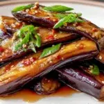 Chinese eggplant in garlic soy glaze cooked until tender, coated in a savory garlic soy sauce, and garnished with green onions and sesame seeds.