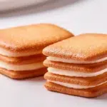 Stacked Shiroi Koibito-style white chocolate sandwich cookies with crisp langue de chat biscuits, shown on a white surface.