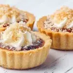 South African jam and coconut tartlets baked with a buttery pastry shell, sweet fruit jam, and a golden coconut topping.