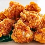 Taiwanese popcorn chicken fried until golden and crispy, seasoned with aromatic spices, and garnished with fresh basil leaves.