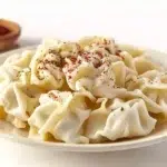 Turkish manti served with tender handmade dumplings filled with seasoned meat, topped with garlic yogurt and spiced butter sauce.