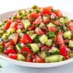 Jerusalem salad with diced tomatoes, cucumbers, bell peppers, fresh parsley, and lemon dressing