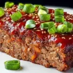 Korean meatloaf with gochujang glaze sliced and topped with sesame seeds and green onions