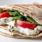 Labneh pita sandwich filled with creamy labneh, fresh vegetables, herbs, and olive oil in warm pita bread