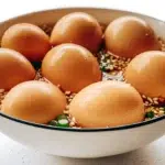 Mayak eggs marinated in soy sauce with garlic, chili, green onions, and sesame seeds served over rice