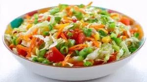 Nigerian vegetable salad with lettuce, cabbage, carrots, cucumbers, tomatoes, sweet corn, boiled eggs, and creamy dressing